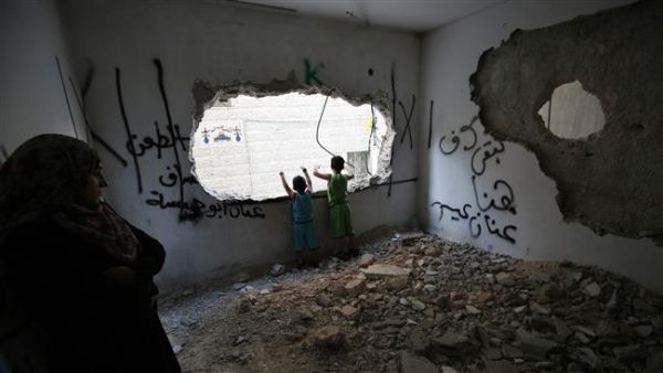 Palestinians stand at a house that was demolished by Israeli authorities in the Qalandia refugee camp. (AFP/File)
