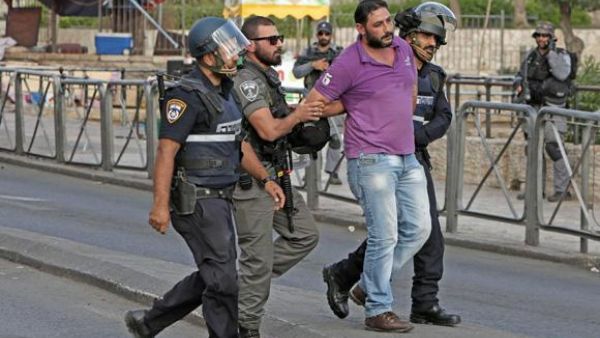 Israeli policemen detain a Palestinian, at the site where two Israeli police officers were stabbed. (AFP/File)