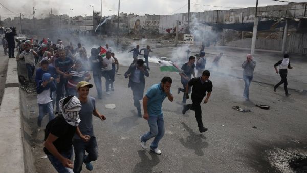 Palestinians run from tear gas smoke during clashes with Israeli security forces at the Qalandiya checkpoint. (AFP/File)