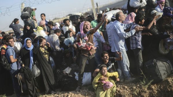Syrians fleeing the war pass through broken border fences and trenches to enter Turkish territory. (AFP/File)