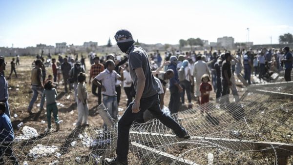 A man stands on the downed border fence. Turkish security personnel have worked to prohibit the Kurds from entering Syria. (AFP/Bulent Kilic)