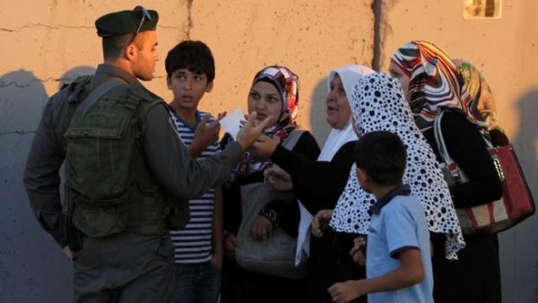 QALANDIA : Palestinian Muslim worshipers talk with an Israeli border guard as they walk towards the Qalandia checkpoint between Ramallah and Jerusalem, in the occupied West Bank. AFP PHOTO/ABBAS MOMANI