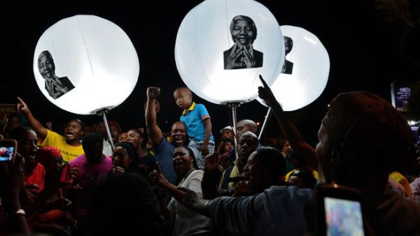 People hold up balloon lamps bearing the image of late former South African president Nelson Mandela during a commemorative ceremony outside the late leader's former home. [AFP]