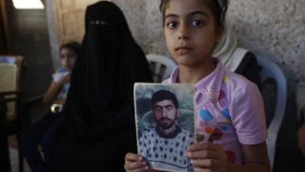 طفلة فلسطينية تحمل صورها لوالدها المعتقل في سجون الإحتلال الإسرائيلية