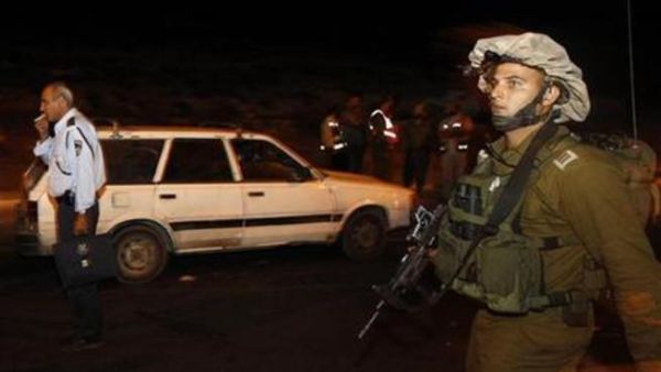 جندي اسرائيلي بجوار السيارة التي قتل فيها اربعة اسرائيليين
