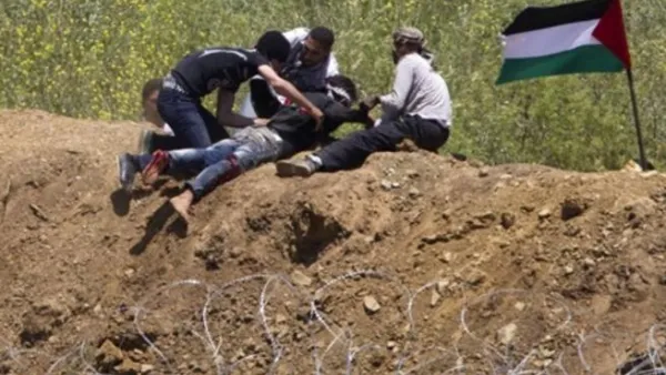 متظاهرون فلسطينييون ينقذون شابا أصيب بالرصاص الإسرائيلي على حدود الجولان 