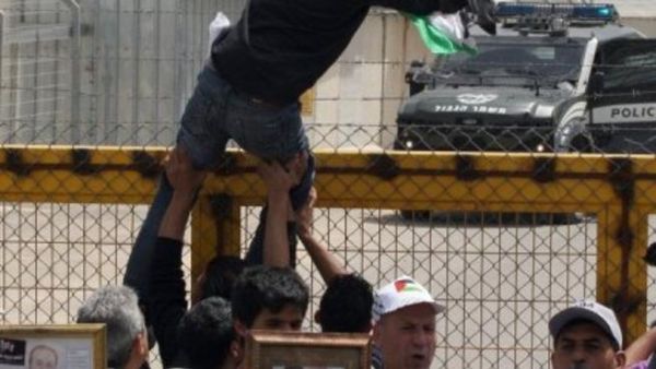 متظاهر يعلق علما فلسطينيا على باب سجن عوفر الاسرائيلية في الضفة
