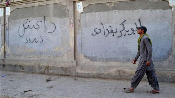 A Pakistani man walks past graffiti reading "Abu Bakr al-Baghdadi," the name of the leader of Daesh, in Quetta, Pakistan. (AFP/Banaras Khan)