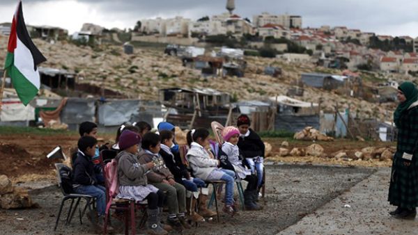 A Palestinian teacher leads a class of Palestinian bedouin children from the Abu Nawar community near the Jewish settlement of Maale Adumim (background), in the West Bank town of al-Azariya, east of Jerusalem. (AFP/file)