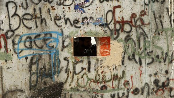 A member of Israeli security forces aims through a hole in the iron gate along the Israeli controversial separation barrier in the West Bank town of Bethlehem. (AFP/File)