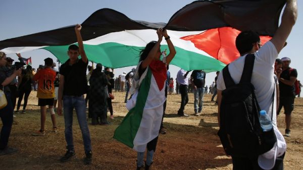 Arab-Israeli protesters hold a large Palestinian flag as they march for the right of return for Palestinian refugees who fled their homes or were expelled during the 1948 war that followed the creation of the state of Israel, near the southern Israeli Bedouin of Rahat on May 12, 2016. (AFP/Ahmad Gharabli)