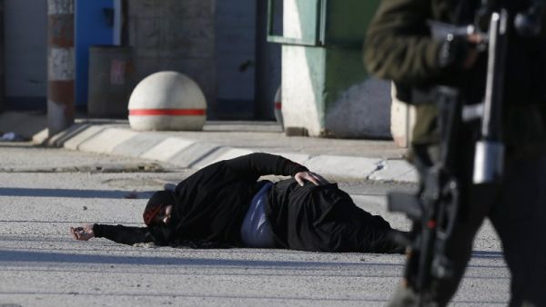 A Palestinian woman lies on the ground after she was shot and wounded by Israeli security forces while approaching the Qalandia checkpoint with a knife, between Jerusalem and the occupied West Bank on December 30, 2016, according to Israeli police. (AFP/Abbas Momani)