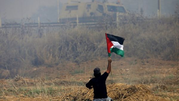 This file photo taken on May 19, 2017 shows Palestinian demonstrator Ibrahim Abu Thurayeh waving a Palestinian flag during clashes with Israeli soldiers (Mohammed Abed/AFP)