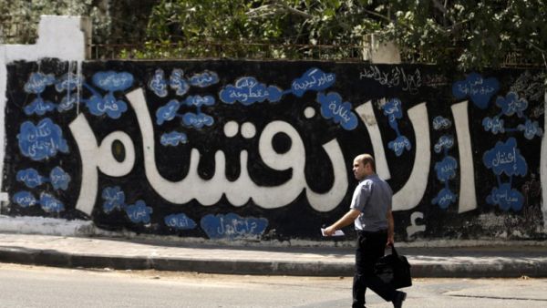 A Palestinian man walks past a graffiti reading in Arabic ''Division'' in Gaza City, on September 17, 2017, after Hamas announced it had agreed to steps toward resolving a decade-long split with the Fatah movement and was ready to hold elections (Mahmud Hams/AFP)