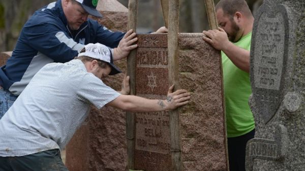 Volunteers from a local monument company help to reset vandalized headstones at Chesed Shel Emeth Cemetery on February 22, 2017 in University City, Missouri [AFP/Michael Thomas]