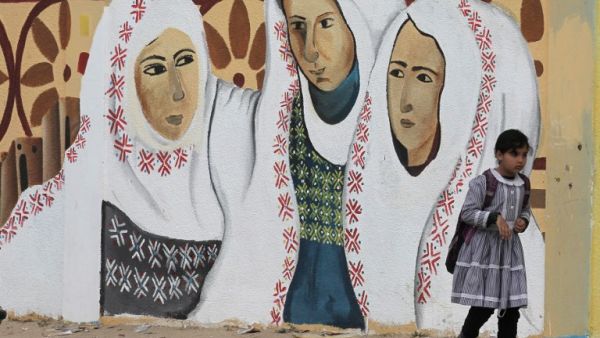A Palestinian girl walks past a mural on a street in Rafah, in the southern Gaza Strip, on March 30, 2017, which marks Land Day. Land Day marks the killing of six Arab Israelis during 1976 demonstrations against Israeli confiscations of Arab land. (AFP/Said Khatib)
