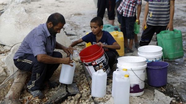 A Palestinian man and children fill containers with water from a broken main. (AFP)