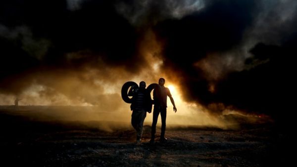 Palestinian protesters carry tyres as smoke billows from burning tyres at the Israel-Gaza border, east of Gaza city. (SAID KHATIB / AFP)