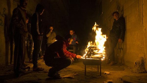 Palestinians gather around a fire during a power cut in the Al-Shati refugee camp in Gaza City, on January 4, 2017. (AFP/Mahmud Hams)