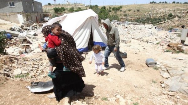 A Palestinian family whose house was demolished by Israeli bulldozers walk past a tent on April 21, 2015, in the southern West Bank village of Ad-Deirat Rifaiyya. (AFP/Hazem Bader)