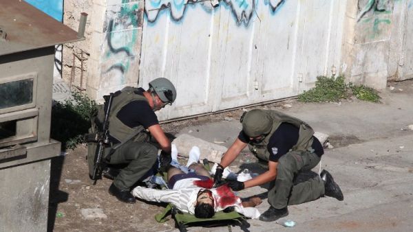 Israeli security forces inspect the body of a Palestinian man who stabbed and lightly wounded an Israeli border guard before being shot dead in the Israeli occupied West Bank city of Hebron, on October 29, 2015. (AFP / Hazem Bader)  