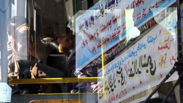 An Egyptian passenger is seen through electoral banners reflected on the windscreen of a public bus in al-Sayyida Zaian district, in downtown Cairo, on November 23, 2010, as the campaign rally for the upcoming November 28, Egyptian general election continues
