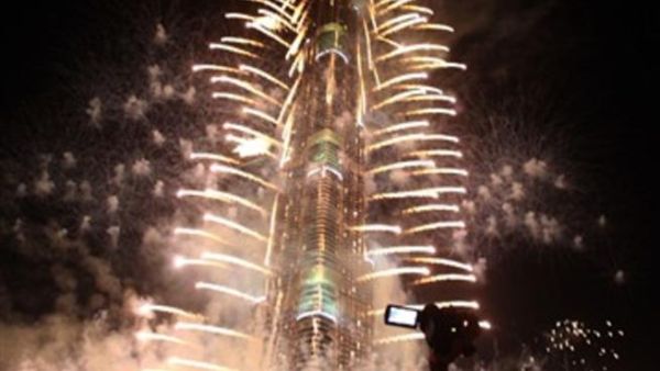 Crowds look at fireworks bursting around Burj Khalifa, the tallest building in the world, marking the New Year at midnight on January 1, 2011 in the Gulf emirate of Dubai. 