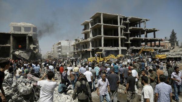 Syrians gather around one of the bombed buildings in Qamishli on July 27, 2016. (AFP/Delil Souleiman)