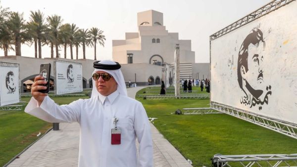 A visitor takes a selfie during an exhibition of artworks depicting Qatari Emir Tamim bin Hamad al-Thani titled "Glorious Tamim: in celebration of national unity " at the garden of the Islamic Museum in Doha on August 20, 2017 (AFP)
