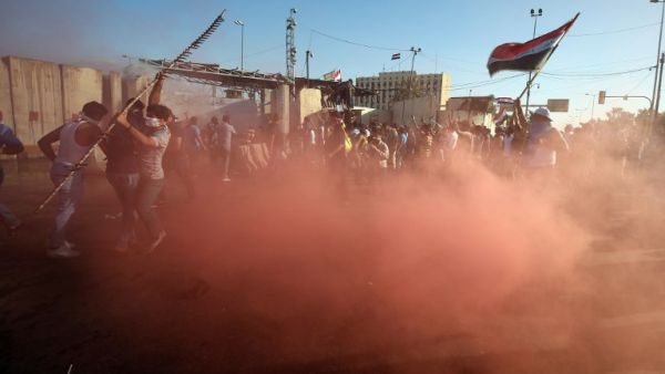 Sadrist protesters outside of Baghdad's Green Zone react to canisters of tear gas. (AFP/Ahmad Al-Rubaye)