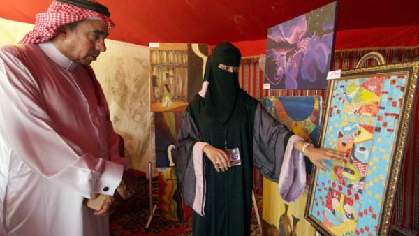 A Saudi woman examines a piece of artwork at a gallery showing. (AFP/File)