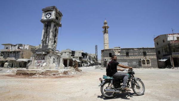  A Syrian man rides his motorbike past the Sunni Grand mosque in the city of Qusayr, in Syria's central Homs province. (AFP/JOSEPH EID)