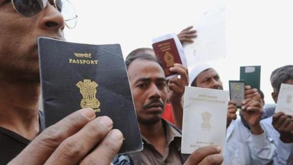 Foreign workers show passports as they wait outside the immigration office in Saudi. [yahoo]
