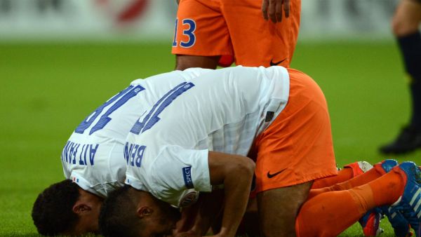 Two Muslim soccer players in France pray during a match (AFP)