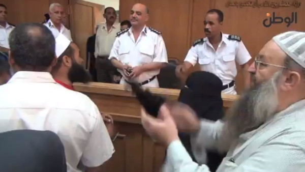 A fully covered woman pounds the desk of the police while leading a chant in Egypt. (screen grab from YouTube)