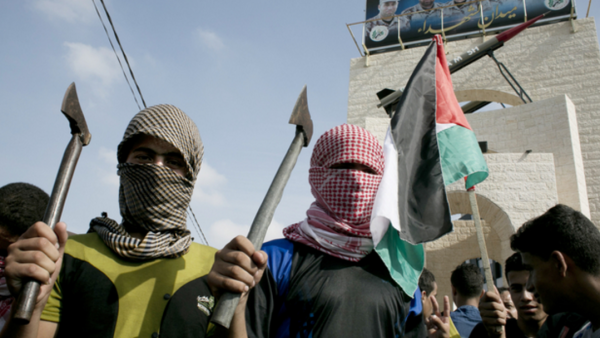 Palestinian students in checkered keffiyehs holding axes. (photo: AFP) 