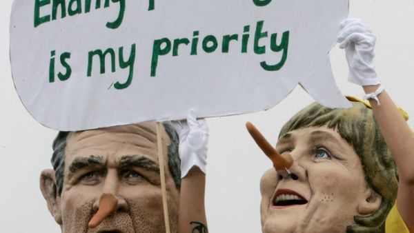 Demonstrators in face masks of world politicians carrying their slogans.
