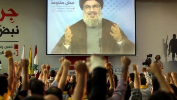 Supporters of Hassan Nasrallah (portrait), the head of Lebanon's militant Shiite Muslim movement Hezbollah raise their fists as they watch him giving a televised address in Beirut last week (AFP)