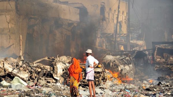A man and woman look at the damages on the site of the explosion of a truck bomb in the centre of Mogadishu, on October 14, 2017 (Mohamed Abdiwahab/AFP)
