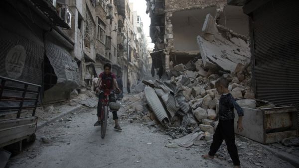 Aleppo residents walk through the rubble of the regime-controlled neighborhood of Karm al-Jabal after an airstrike on September 18, 2016. (AFP/Karam Al-Masri)