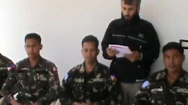 An image grab taken from a video uploaded on YouTube on May 08, 2013 reportedly shows a man reading a statement at an undisclosed location in Syria, behind four abducted Filipino UN peacekeepers. (AFP/ YouTube)