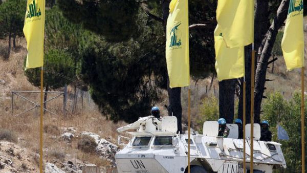 LEBANON, MARJAYOUN : Spanish peacekeepers of the United Nations Interim Force in Lebanon (UNIFIL) patrol in their armoured vehicles near a placard of Hezbollah on July 23, 2013 in the southern Lebanese city of Marjayoun. AFP PHOTO MAHMOUD ZAYYAT