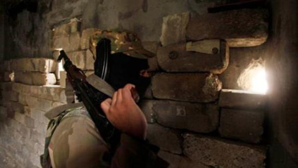 A member of the Islamic State of Iraq and the Levant carries his weapon as he looks through a hole in a wall in Sheikh Saeed neighbourhood December 4, 2013. [AFP]
