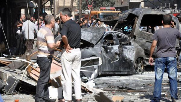 SYRIA, DAMASCUS : A handout picture released by the Syrian Arab News Agency (SANA) shows Syrians looking at burned-out car bombs after an attack that at least killed seven people and wounded 62 on July 25, 2013 in Jaramana suburb in southeast Damascus. AFP PHOTO / HO / SANA 