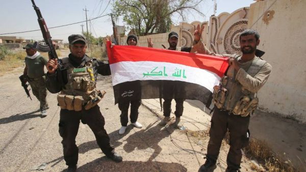 Members of Iraq's mainly Shiite Popular Mobilization Units hold up an Iraqi flag.  The volunteer militia, though split into several factions, has been instrumental in the fight against Daesh militants in Iraq.  (AFP/File).  