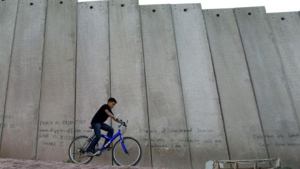 A boy rides his bike next to Israel's separation wall, which cuts off the West Bank.  Social media platform Snapchat featured the West bank July 9 after outcry following it's Tel Aviv feature on the one year anniversary of last summer's Gaza war.  (AFP/Ahmad Gharabli)