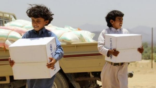 Children carry supplies handed out by UNICEF outside the Yemeni capital Sanaa. Heavy airstrikes and ground fighting across the country have made it extremely difficult for humanitarian aid to reach Yemen's civilians. (AFP/File)