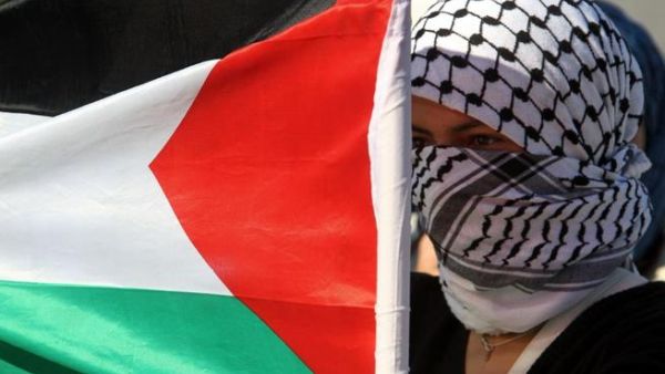 فلسطينية ترفع العلم الوطني بالقرب من حاجز اسرائيلي خلال تظاهرة احتجاج ضد العدوان على غزة في نابلس بالضفة الغربية/أ.ف.ب