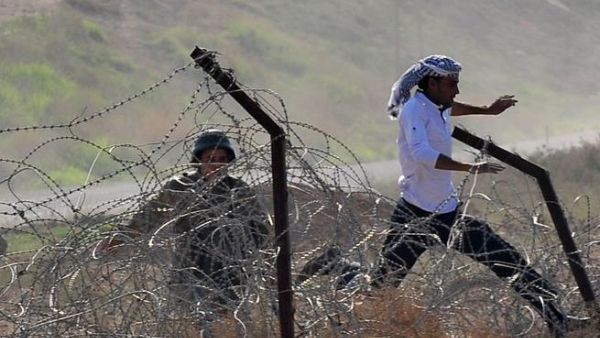 مواطن سوري يحاول الهرب في تجاه تركيا في حين يتصدى له جندي تركي/أ.ف.ب