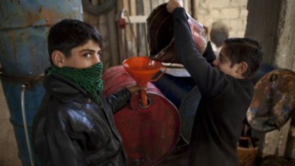 اطفال يعبأون ديزل للتدفئة في بلدة اعزاز شمال سوريا/أ.ف.ب